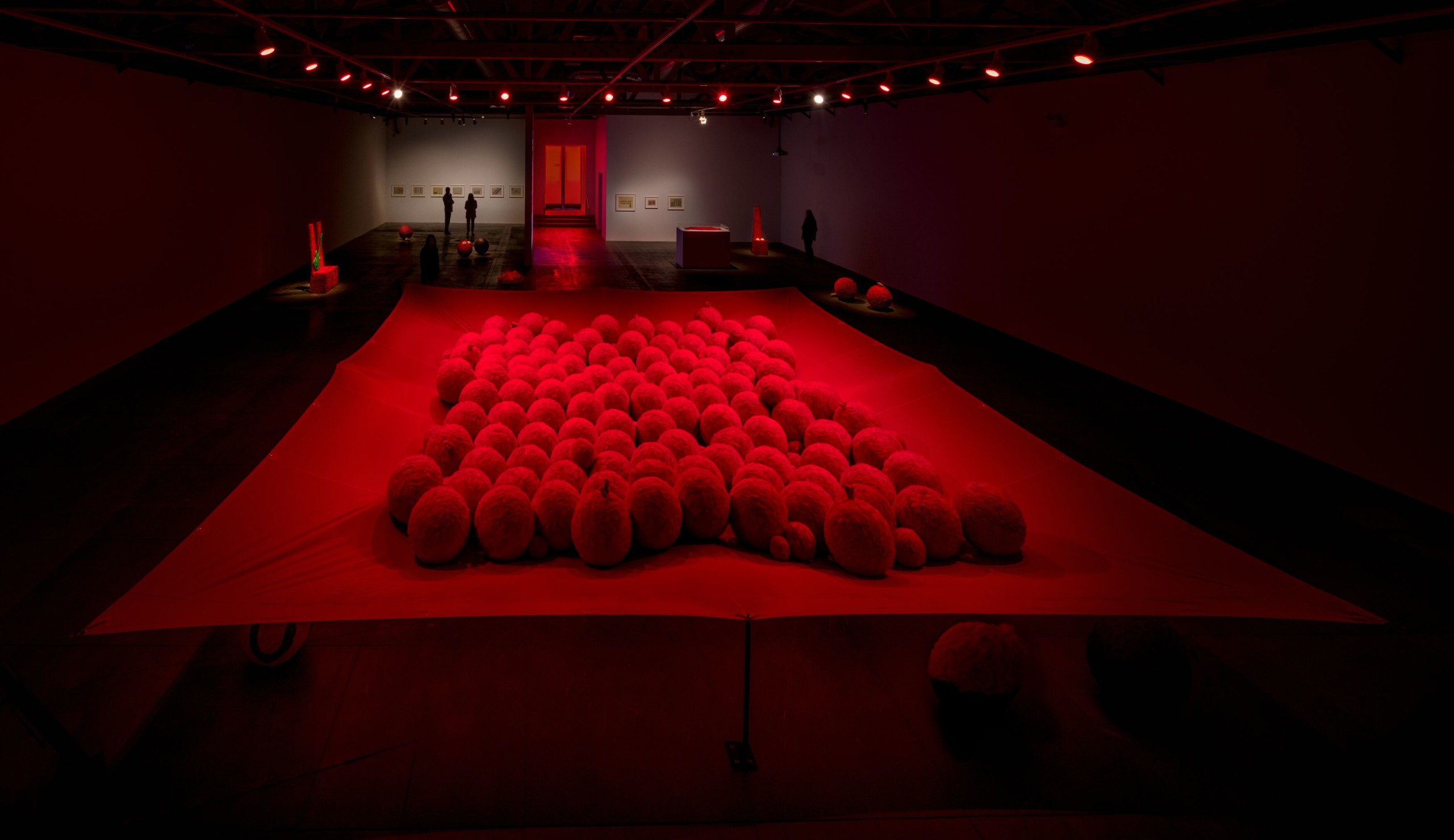 Gallery installation with red lighting on large-scale balls on fabric