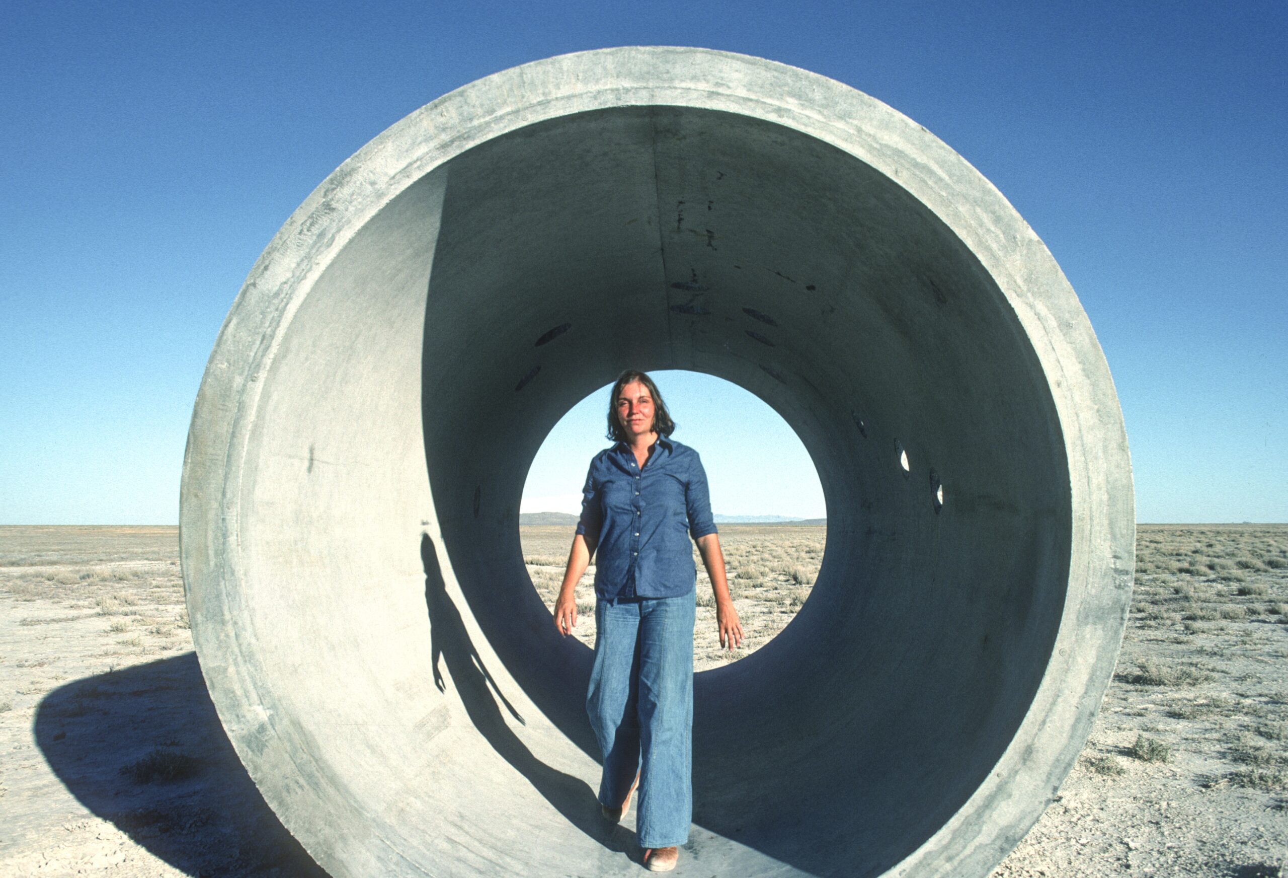 Nancy Holt standing in one of the Sun Tunnels in Utah's Great Basin Desert in 1976